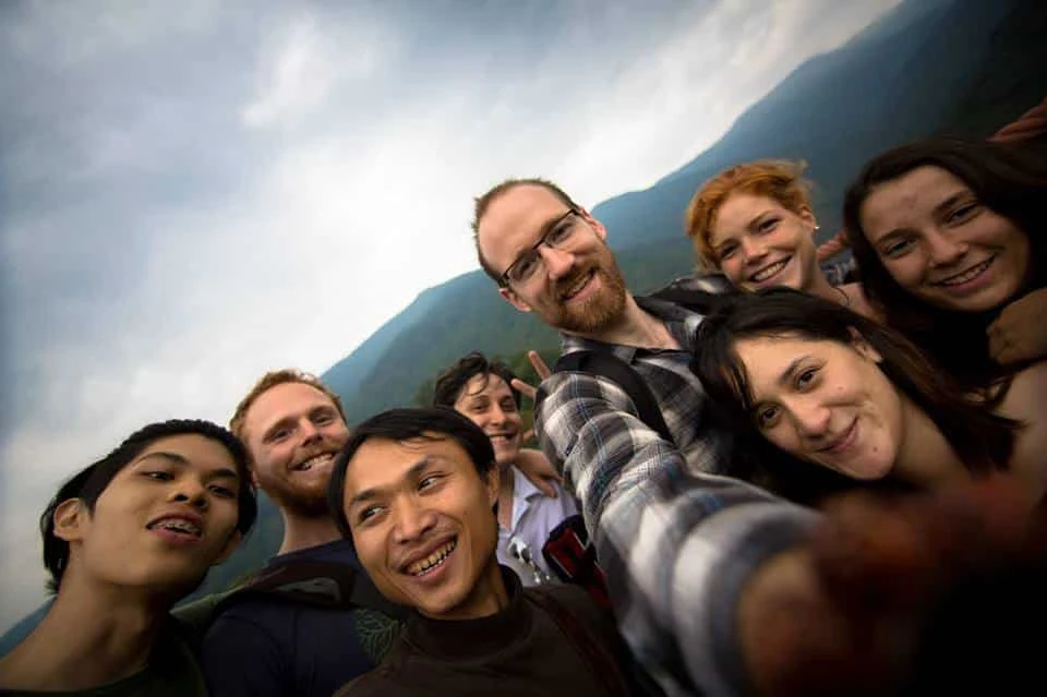 A group of smiling volunteers together with hills behind them