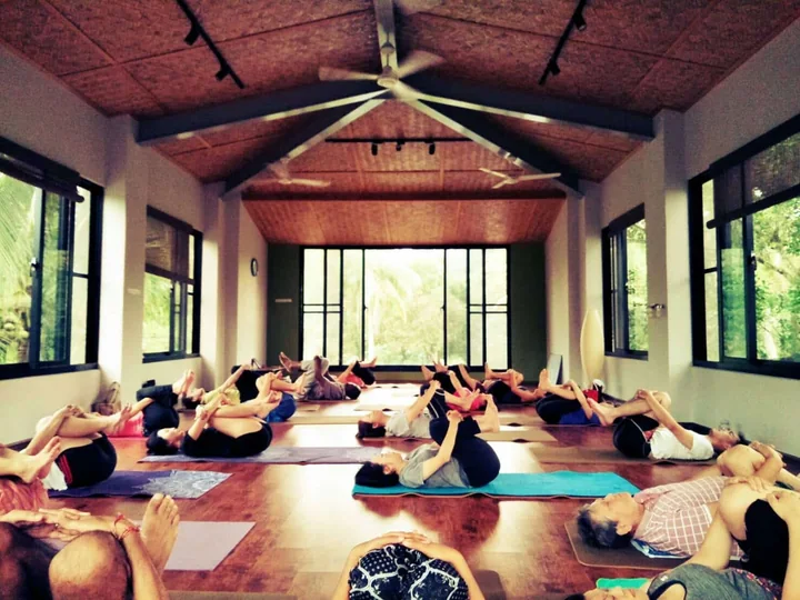 Participants practicing yoga indoors in a bright wood-beamed studio